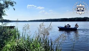 Na zdjęciu policjanci na łódce płynącej po jeziorze.
