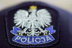 Na zdjęciu widoczna policyjna czapka z naszywką, na której widnieje orzeł w koronie, a pod nim niebieska wstęga z napisem POLICJA.