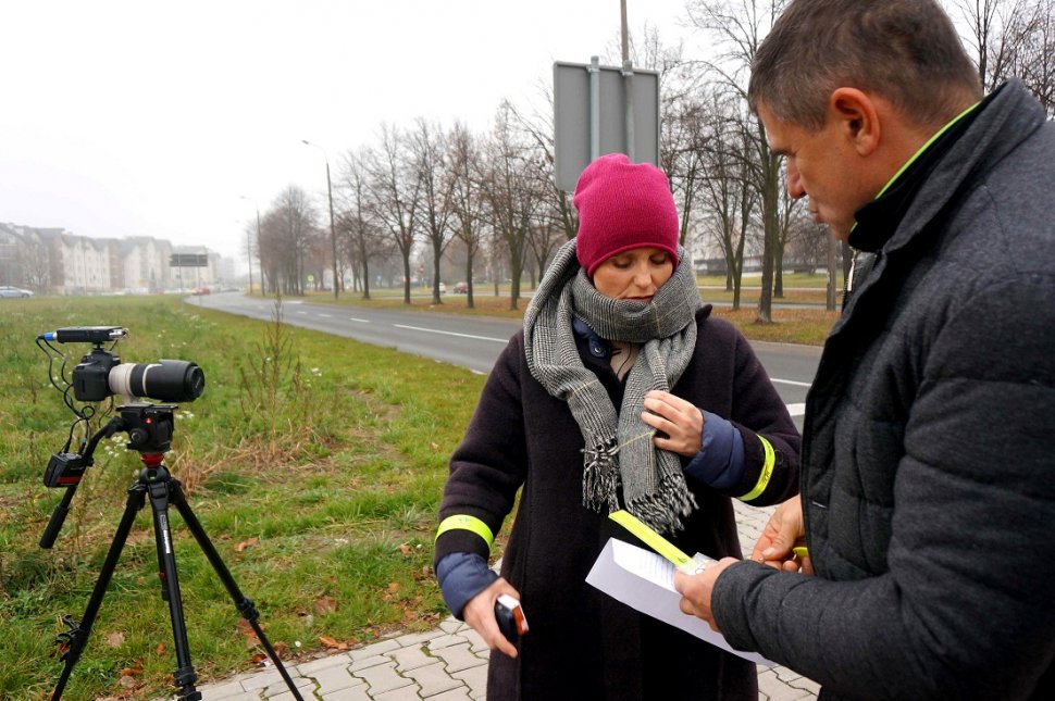 Na zdjęciu aktorka Kinga Preis obok nieumundurowany policjant, po prawej stronie stoi aparat na statywie. 