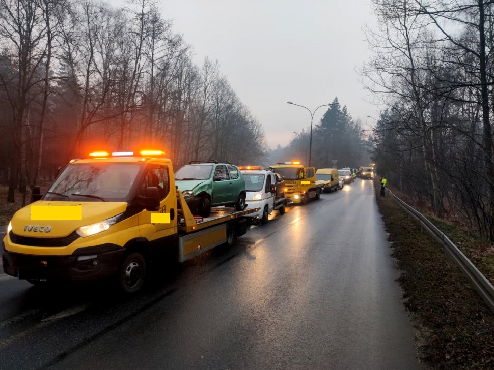 Na lawetach widoczne są pojazdy uszkodzone w kolizji drogowej. 