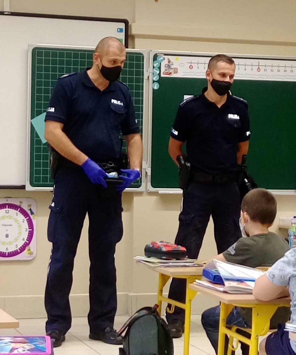 Dwóch policjantów dzielnicowych na spotkaniu w klasie z dziećmi. 