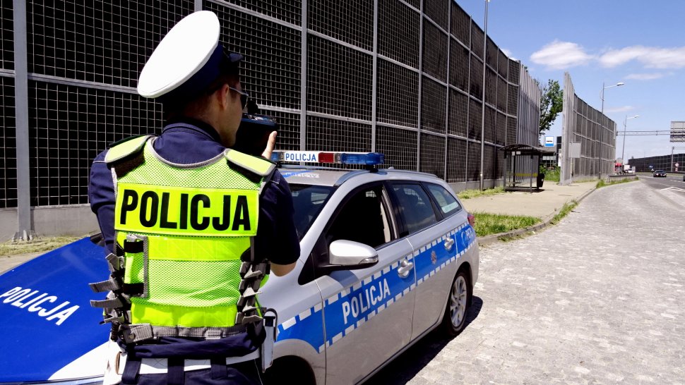 Policjant wydziału ruchu drogowego mierzy prędkość niezderzającego pojazdu. 