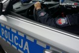 Na obrazku drzwi radiowozu z napisem &amp;quot;policja&amp;quot;, widoczny rękaw munduru policjanta, który ma otworzone okno, z widoczną naszywką &amp;quot;Wydział Ruchu Drogowego&amp;quot;