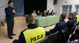 Obrazek przedstawia przemawiającego Komendanta Miejskiego Policji w Tychach insp. Andrzeja Trzcińskiego, za nim przedstawiciele administracji siedzący przy stoliku, widać także umundurowanych policjantów siedzących przodem do przemawiającego