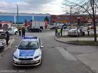 Obrazek przedstawia oznakowany radiowóz, za nim po bokach rozbite pojazdy, wokół nich ludzie i policjanci wykonujący czynności na miejscu wypadku