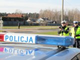 Obrazek przedstawia widoczny z radiowozu napis POLICJA, za nim dwóch policjantów mierzących prędkość