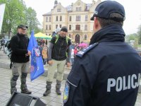 Obrazek przedstawia stojących na scenie po lewej stronie: dwóch nieumundurowanych policjantów, jeden z nich trzyma flagę &quot;Wyprawa dla Jasia&quot; drugi na plecach w foteliku trzyma chłopca-Jasia. Po prawej tyłem Komendant Miejski Policji w Tychach.