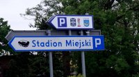 Obrazek przedstawia tabliczkę informacyjną, która wskazuje strzałką stadion