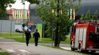 Zdjęcie przedstawia dwóch patrolujących policjantów, widoczny także wóz straży pożarnej oraz w tle stadion