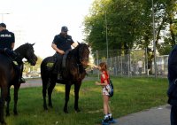 Obrazek przedstawia policjanta na koniu, którego głaszcze dziewczynka