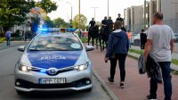 Obrazek przedstawia radiowóz, policjantów na koniach oraz osoby, które idą na mecz