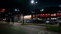 Obraz nocą, widoczni policjanci na koniach, po prawej stronie mijają stadion miejski