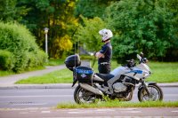 Na zdjęciu widoczny policjant stojący w kasku obok motocykla