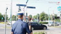 Na zdjęciu policjant z drogówki stojący tyłem, w rejonie skrzyżowania z sygnalizacją świetlną