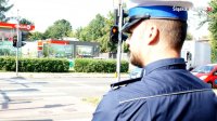 Na zdjęciu policjant ruchu drogowego stojący przy skrzyżowaniu z sygnalizacją świetlną