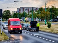 W rejonie skrzyżowania policjant zagląda do bagażnika zatrzymanego pojazdu, widoczne także inne samochody