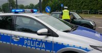 Na zdjęciu widoczny radiowóz i policjant, który wskazuje innemu kierowcy drogę na objazd.