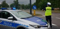 Na zdjęciu widoczny policjant który kieruje ruchem, za nim znajduje się radiowóz.