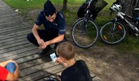 Policjant kuca przy chłopcu, któremu dał ulotkę &quot;Kręci mnie bezpieczeństwo nad wodą&quot;.