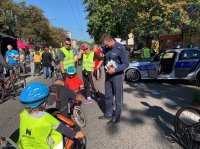 Na zdjęciu widoczny policjant z wydziału ruchu drogowego, radiowóz oraz inni uczestnicy &quot;Europejskiego Dnia Bez Samochodu&quot;.