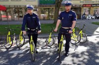 Dwaj umundurowani policjanci z wydziału ruchu drogowego na rowerach.