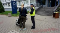 Policjantka z drogówki rozmawia przed komendą z kobietą z wózkiem.