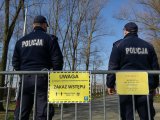 dwóch umundurowanych policjantów oraz żółte tabliczki informujące o zakazie wstępu na teren OW Paprocany