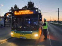 Umundurowany policjant kontroluje autobus komunikacji miejskiej.