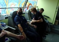 Policjanci wydziału ruchu drogowego tyskiej komendy oddają krew, pielęgniarka asystuje.
