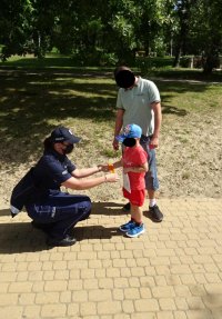 Policjantka przekazuje chłopcu gadżety profilaktyczne, obok stoi tata chłopca.