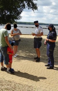 Policjanci rozmawiają z rodziną o bezpieczeństwie nad woda podczas spotkania profilaktycznego nad zalewem Paprocany.