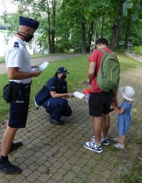 Policjanci rozmawiają z mężczyzną i jego córką o bezpieczeństwie nad wodą.