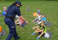 Policjantka rozdaje dzieciom kolorowanki.