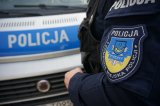 Naszywka na mundurze z napisem &quot;Komenda Miejska Policji w Tychach, Policja, Tychy&quot; w tle radiowóz.
