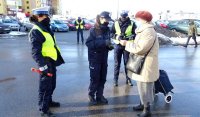 Policjanci stoją obok kobiety, jedna z policjantek przekazuje jej odblask.