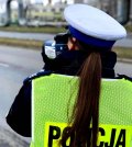 Policjantka w odblaskowej kamizelce trzyma ręczny miernik prędkości.