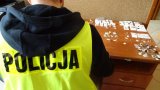 na pierwszym planie zdjęcia znajduje się nieumundurowany funkcjonariusz w żółtej odblaskowej kamizelce z napisem POLICJA.  Przed nim na biurku znajduje się zabezpieczona biżuteria .