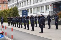Policjanci wraz z funkcjonariuszami Straży Pożarnej oraz Straży Miejskiej oddają honor przed budynkiem Komendy Miejskiej Policji w Tychach.