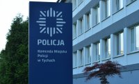 Niebieski baner z logiem przed budynkiem Komendy Miejskiej Policji w Tychach.