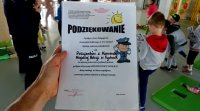 Podziękowanie dla policjantów za przeprowadzoną prelekcje, w tle widoczne dzieci i policjantka.