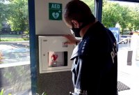 Na zdjęciu widoczny defibrylator AED oraz umundurowany policjant.