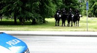 Policjanci na koniach służbowy, z lewej strony widoczna część radiowozu.