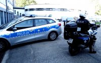 Policjant na motocyklu, widoczny radiowóz.