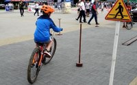 Chłopak na rowerze omija znak drogowy.