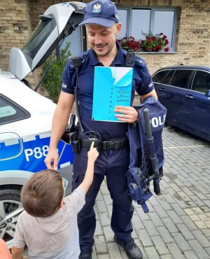 Policjant trzyma w ręce podziękowania od dzieci.
