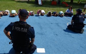 Skulone dzieci prezentują policjantom w jaki sposób należy się bronić przez atakiem groźnego psa.