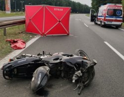 Motocykl leżący na ziemi, parawan a z tyłu karetka.