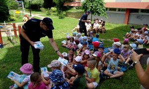 Policjanci rozdają dzieciom edukacyjne książeczki.