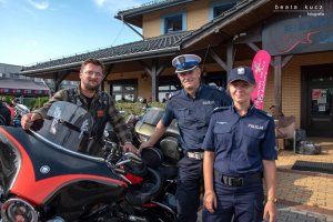 Policjanci stoją obok motocyklisty.