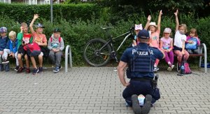 Policjant skierowany w kierunki dzieci, które głoszą się do odpowiedzi.